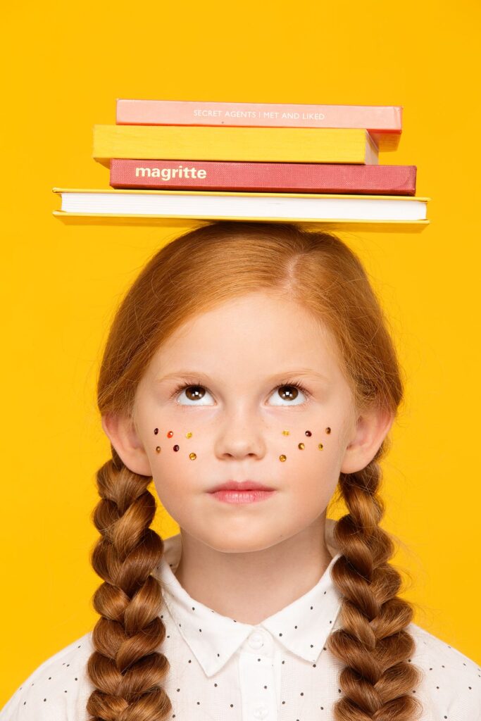 Дівчинка з книжками на голові символізує підготовку до навчання за кордоном