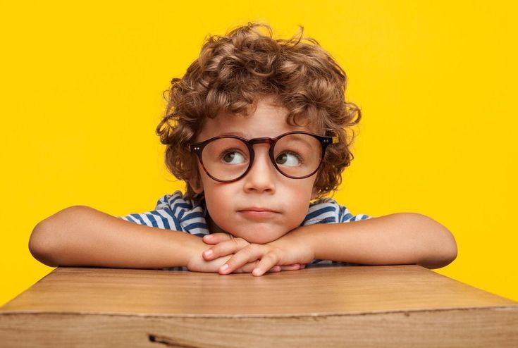 Хлопчик у окулярах задумався за столом — як мистецька освіта підвищує мотивацію і креативність