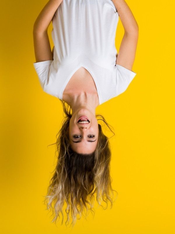 Дівчина догори ногами на жовтому фоні — стрес і втома від стандартизованого тестування