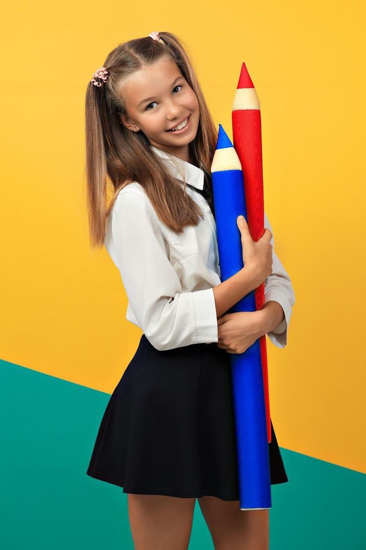 Учениця тримає великі олівці — символ візуальних опор, чітких інструкцій і структурованого навчання для дітей з РАС.