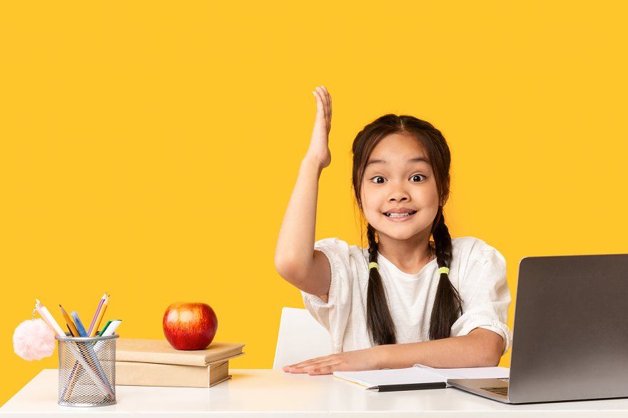 Дитина піднімає руку біля ноутбука — приклад контролю прогресу та перевірки оцінок в електронному журналі