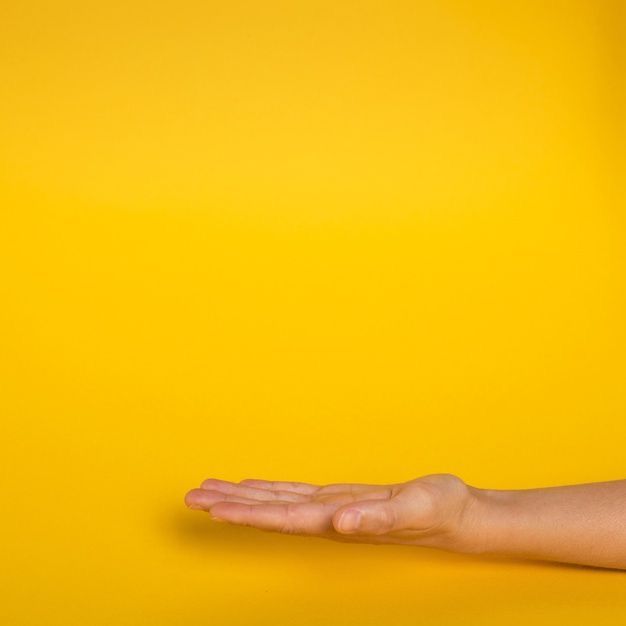 Рука на жовтому фоні як символ подання заяви до школи на зміну форми навчання